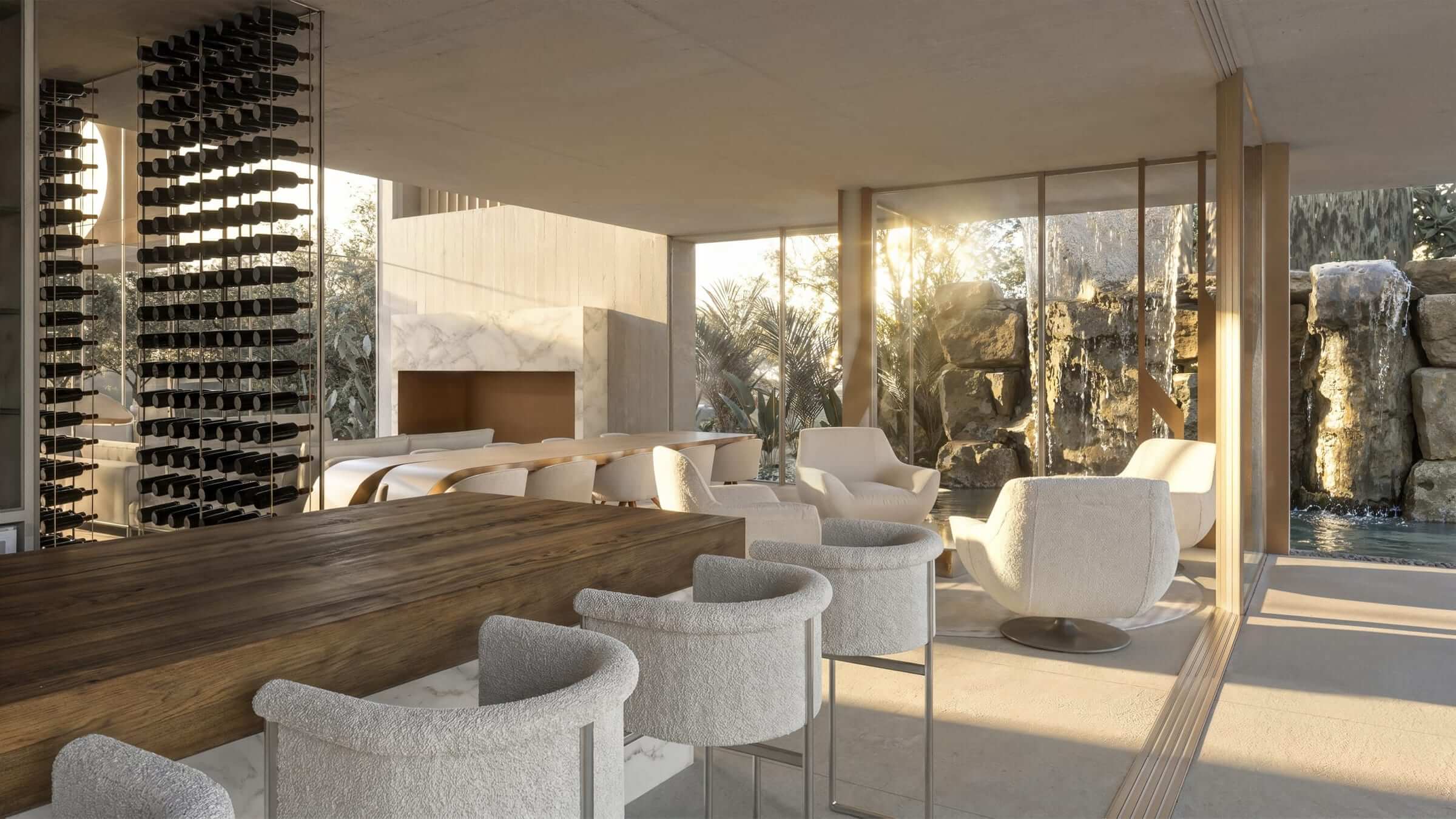 The gourmet space open to the stone waterfall at dusk, between columns of bottles and pale armchairs.