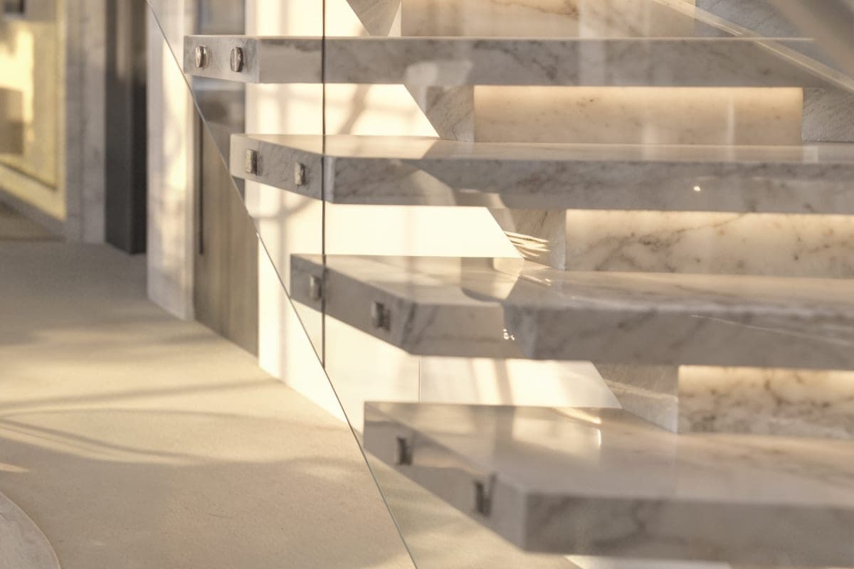 Cantilevered marble stair treads with golden veining, held by a frameless glass balustrade.